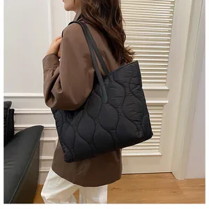 Detail of black quilted tote bag with wave stitching and long shoulder straps