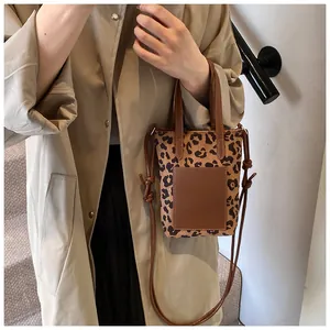 Detail of mini leopard print canvas tote bag with brown leather patch and shoulder strap