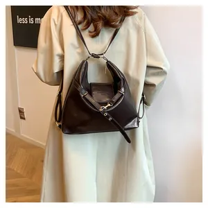 Detail of vintage dark brown leather backpack showing gold hardware on beige trench coat