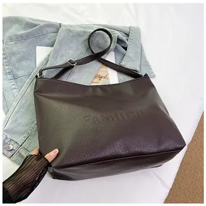 Detail of the brown leather tote bag showing fine litchi texture and fashion embossing
