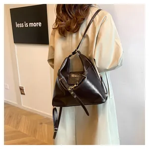 Detail of vintage dark coffee leather tote bag with adjustable straps on a beige trench coat