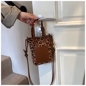 Detail of leopard print crossbody phone bag hanging on a white door handle with strap
