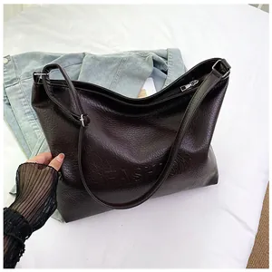 Detail of dark brown tote bag with embossed FASHION text and lychee grain texture