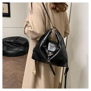 Detail of soft black leather texture and gold hardware buckle on a large tote bag