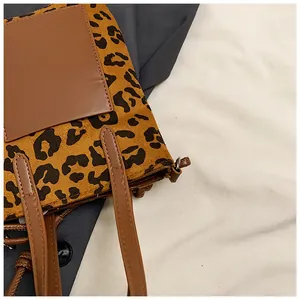 Detail of leopard print faux fur handbag with brown leather handles and fine stitching