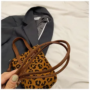 Detailed view of leopard print handbag featuring brown braided leather texture handles