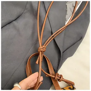 Close-up of knotted brown leather shoulder strap with visible stitching detail