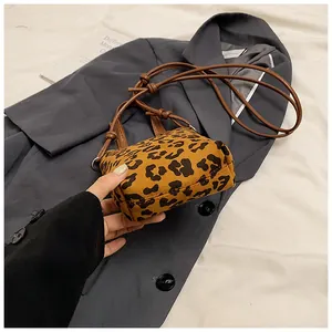 Close-up of leopard print crossbody bag with brown leather strap on grey blazer