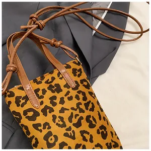 Close-up of leopard print mini bag with brown top handles and knotted strap detail