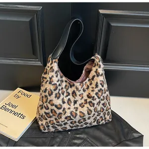 Detail der Leoparden-Kunstfelltextur und schwarzer Lederriemen an einer trendigen Hobo-Bag
