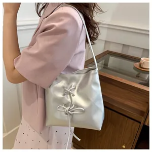 Détail du sac seau en similicuir argenté avec nœud décoratif et détails de laçage