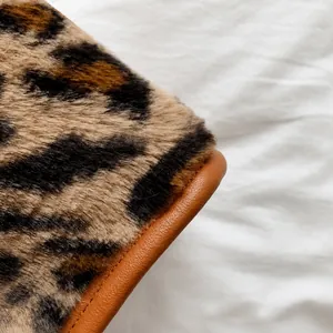 Macro detail of leopard print faux fur material with brown textured leather piping trim