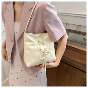Détail du sac à main crème avec un nœud élégant et un design de laçage croisé