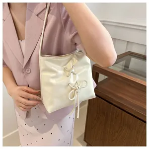 Détail du sac crème avec œillets argentés, design à lacets et nœud décoratif chic