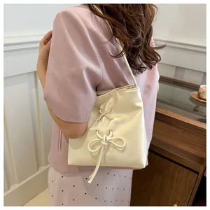 Détail du sac seau blanc crème avec un nœud à lacets sur un cuir synthétique PU souple