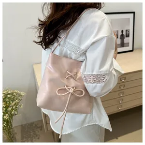 Détail du sac seau rose avec des nœuds décoratifs et un design à lacets croisés