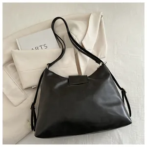 Close-up of black leather Hobo bag with gold hardware and adjustable strap on a neutral base