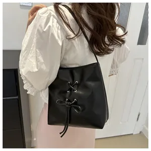 Détail du sac seau noir avec nœud papillon et œillets métalliques sur mannequin