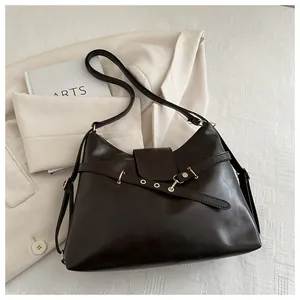 Close-up of retro brown leather shoulder bag with gold hardware and flap detail