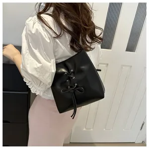 Détail du sac seau noir avec nœud papillon et lacets porté à l'épaule par un mannequin