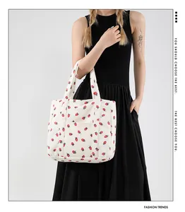 Detail of a large corduroy tote bag featuring a cute red strawberry print and outer pocket