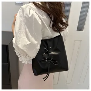 Vue latérale d'un sac seau en cuir noir avec nœud papillon porté par un mannequin élégant