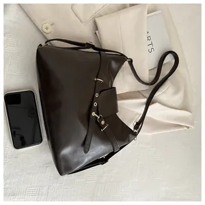 Detail of dark brown leather tote featuring adjustable strap and fashion embossed flap