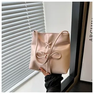 Détail du sac seau rose clair avec nœud décoratif et bandoulière fine et élégante