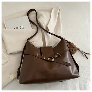 Close-up of brown PU leather shoulder bag with gold hardware and plush bear charm