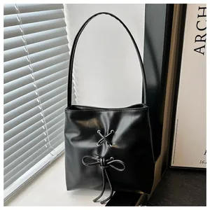 Détail du sac seau noir en similicuir avec nœud décoratif et fines anses souples