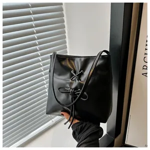 Gros plan sur un sac seau noir en similicuir brillant avec un joli nœud décoratif