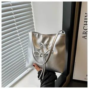 Détail du sac seau argenté avec nœud papillon dans un décor intérieur minimaliste