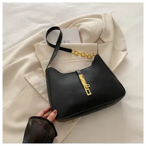 Détail du sac hobo en cuir noir avec fermoir à piston doré et chaîne en métal
