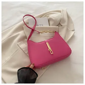 Détail du sac demi-lune rose avec boucle métallique dorée et chaîne sur textile blanc