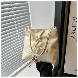 Détail du sac seau blanc crème avec un nœud élégant et de fines bretelles d'épaule