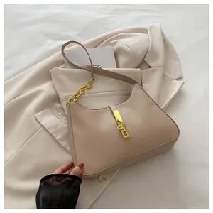 Détail du sac hobo beige avec fermoir piston doré et chaîne sur une veste claire