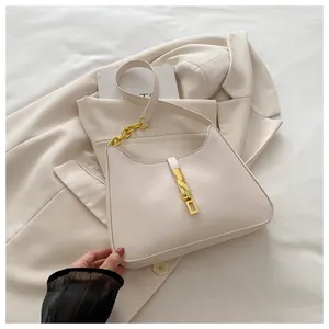 Détail du sac crème avec fermoir doré et chaîne métallique sur un blazer beige chic