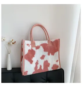 Borsa tote in peluche con stampa mucca rosa e bianca in un ambiente accogliente sul divano