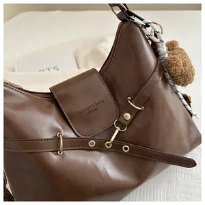 Detail of dark brown leather tote featuring gold hardware and a cute teddy bear charm