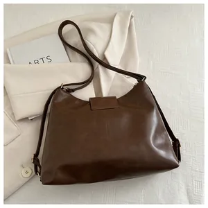 Detail of dark brown PU leather tote bag with adjustable strap on beige blazer