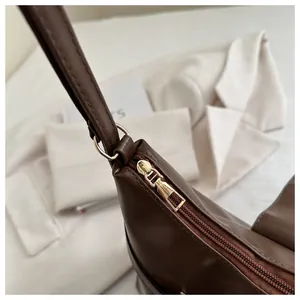 Detail shot of smooth brown leather texture with high-quality golden zipper and metal ring