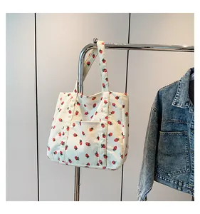 Detail of white corduroy tote bag with red strawberry print and external pocket