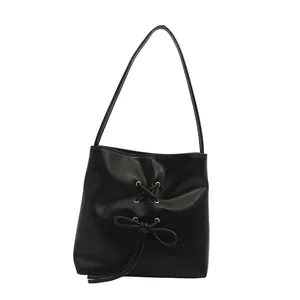 Sac seau noir minimaliste avec nœud élégant et fine bandoulière sur fond blanc épuré