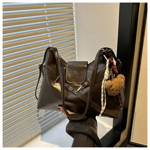 Detail of dark chocolate PU leather handbag with crisscross straps and metal eyelets
