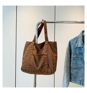 Detail of retro brown corduroy tote bag with red floral print and front pocket