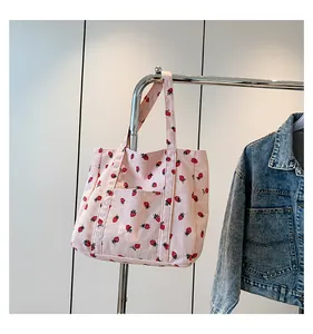Pink corduroy tote bag featuring red strawberry patterns and a front pocket detail