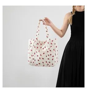 Detailed shot of white corduroy tote bag with red strawberry prints and outer pocket