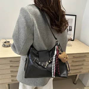 Large black leather tote bag with long straps and plush bear charm for daily commute