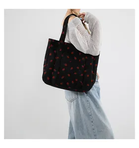 Detail of strawberry print corduroy tote bag showing large front pocket and long handles