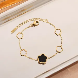 Detail of gold stainless steel bracelet with black and hollow five-petal flower charms